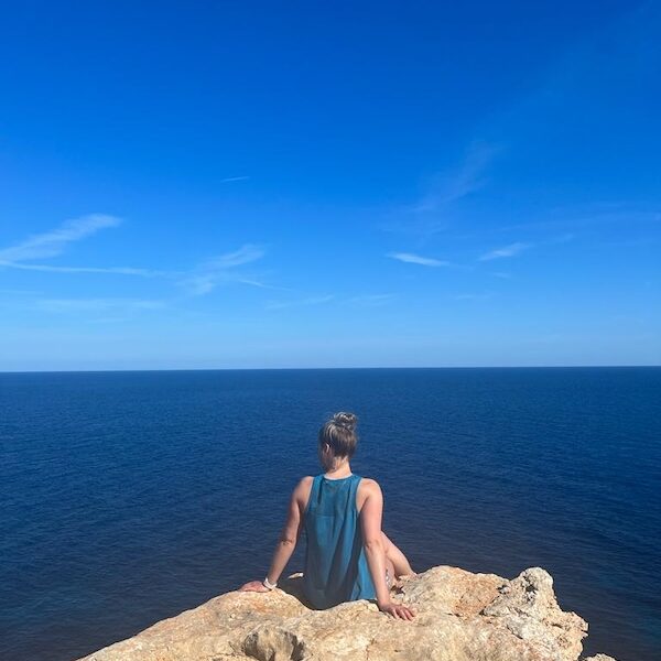 Marissa op een rots, strakblauwe lucht en zee